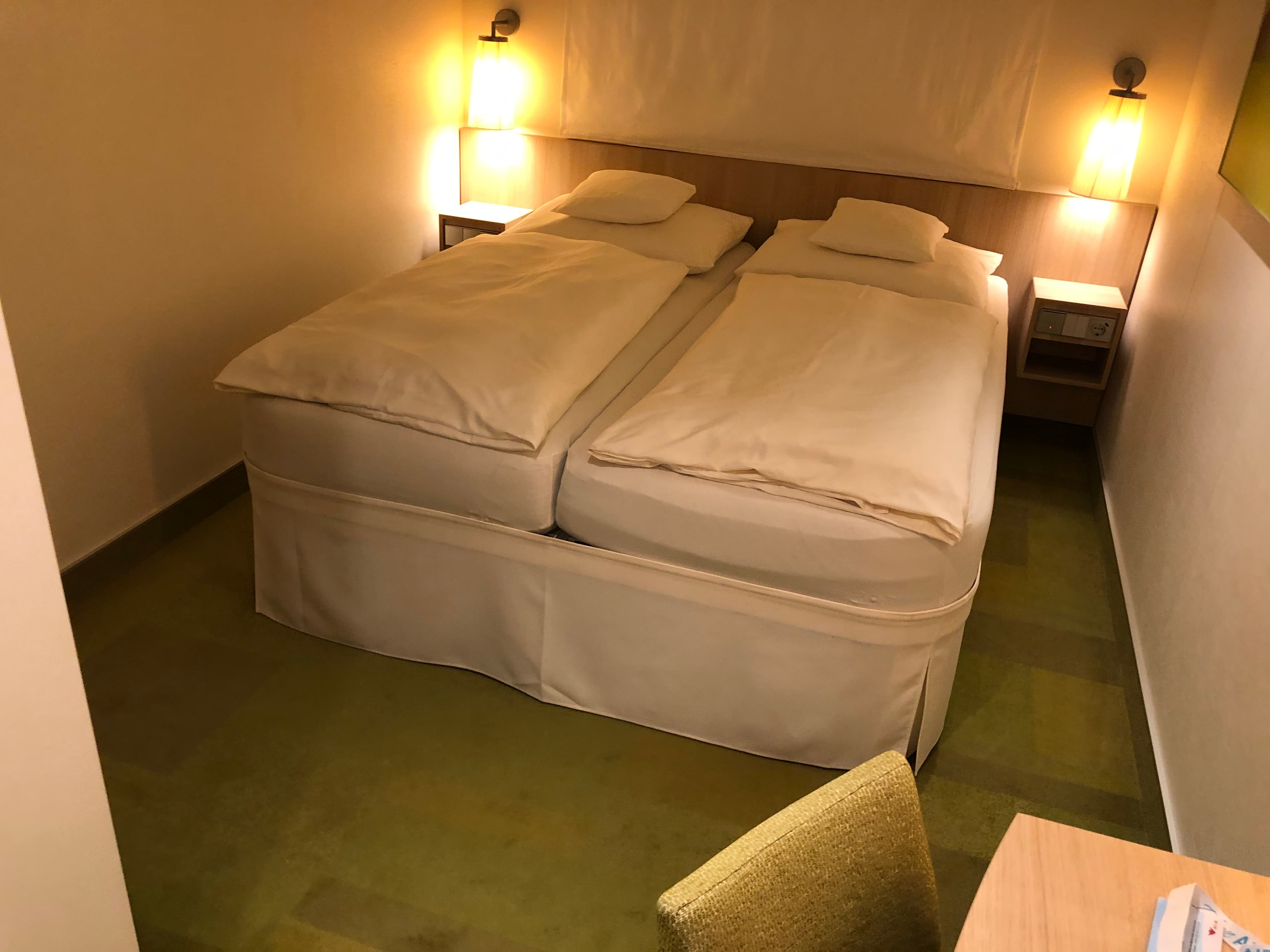 AIDA Innenkabine — Doppelbett mit warmer Wandleuchte