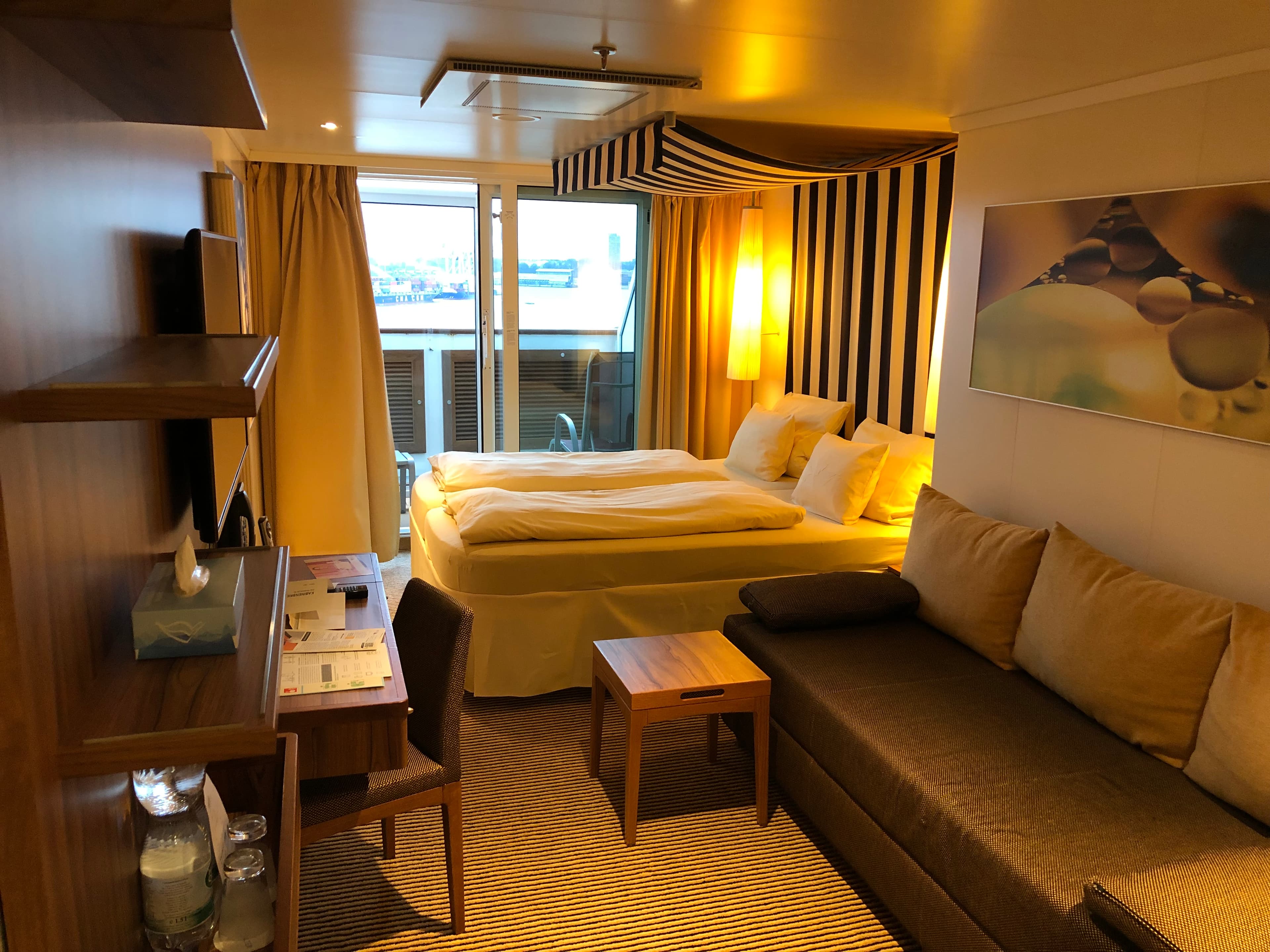 Vorschiffskabine — warmer Kabinenraum mit Sofa und Balkonausblick