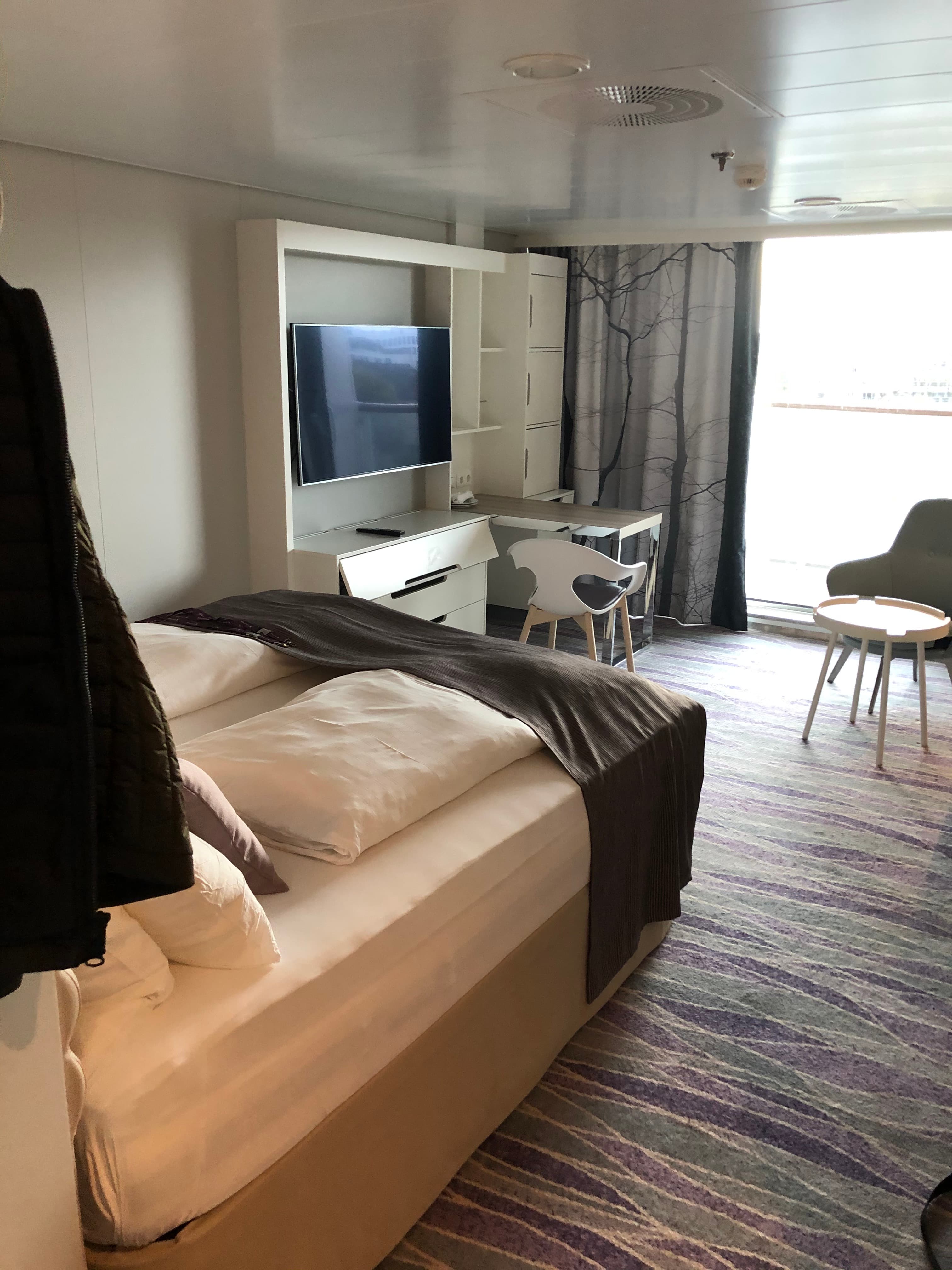 Mein Schiff Suite — Schlafbereich mit Doppelbett und lila Akzentwand