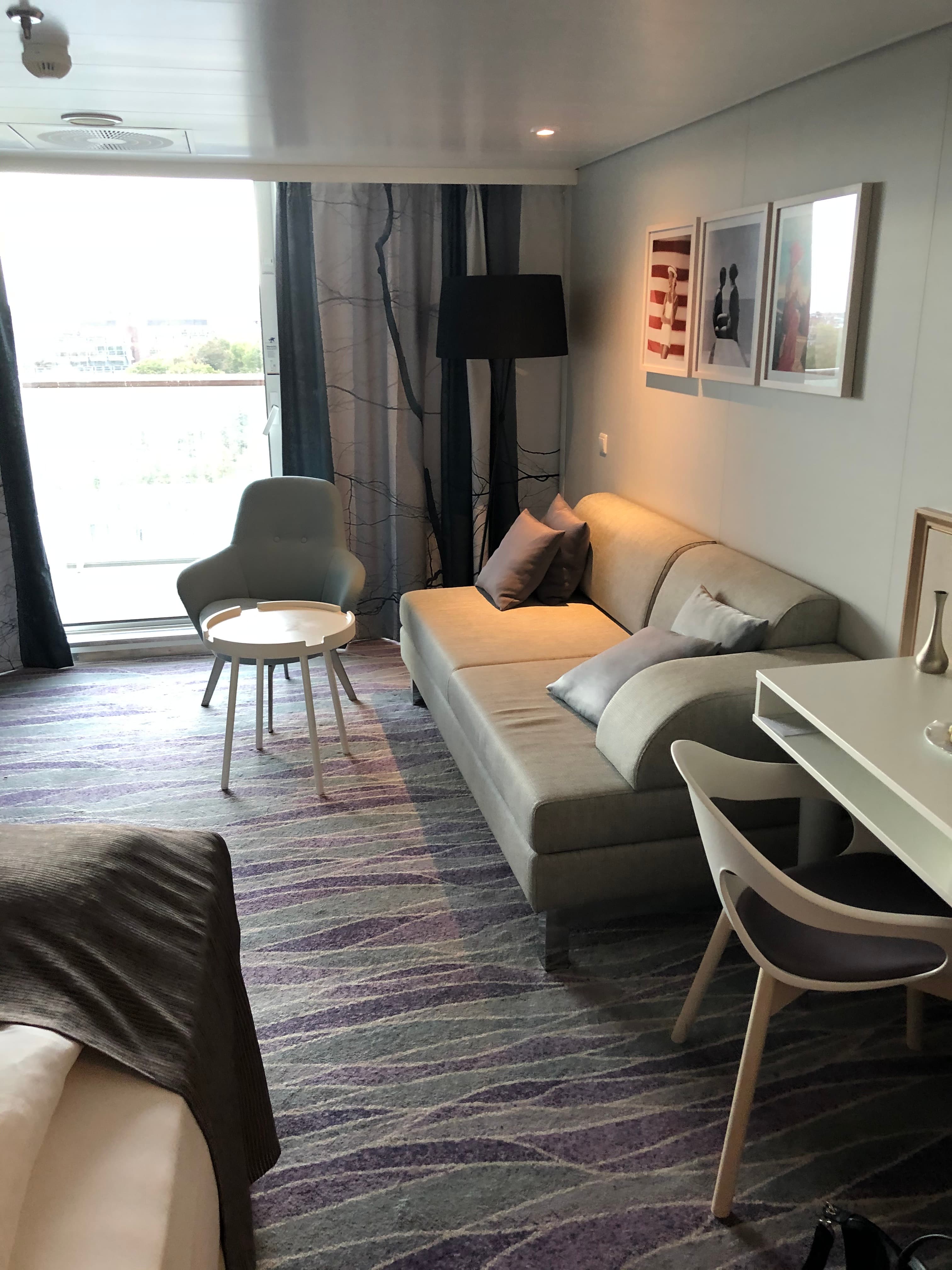 Mein Schiff Suite — Wohnbereich mit Sofa, Esstisch und großem Fenster